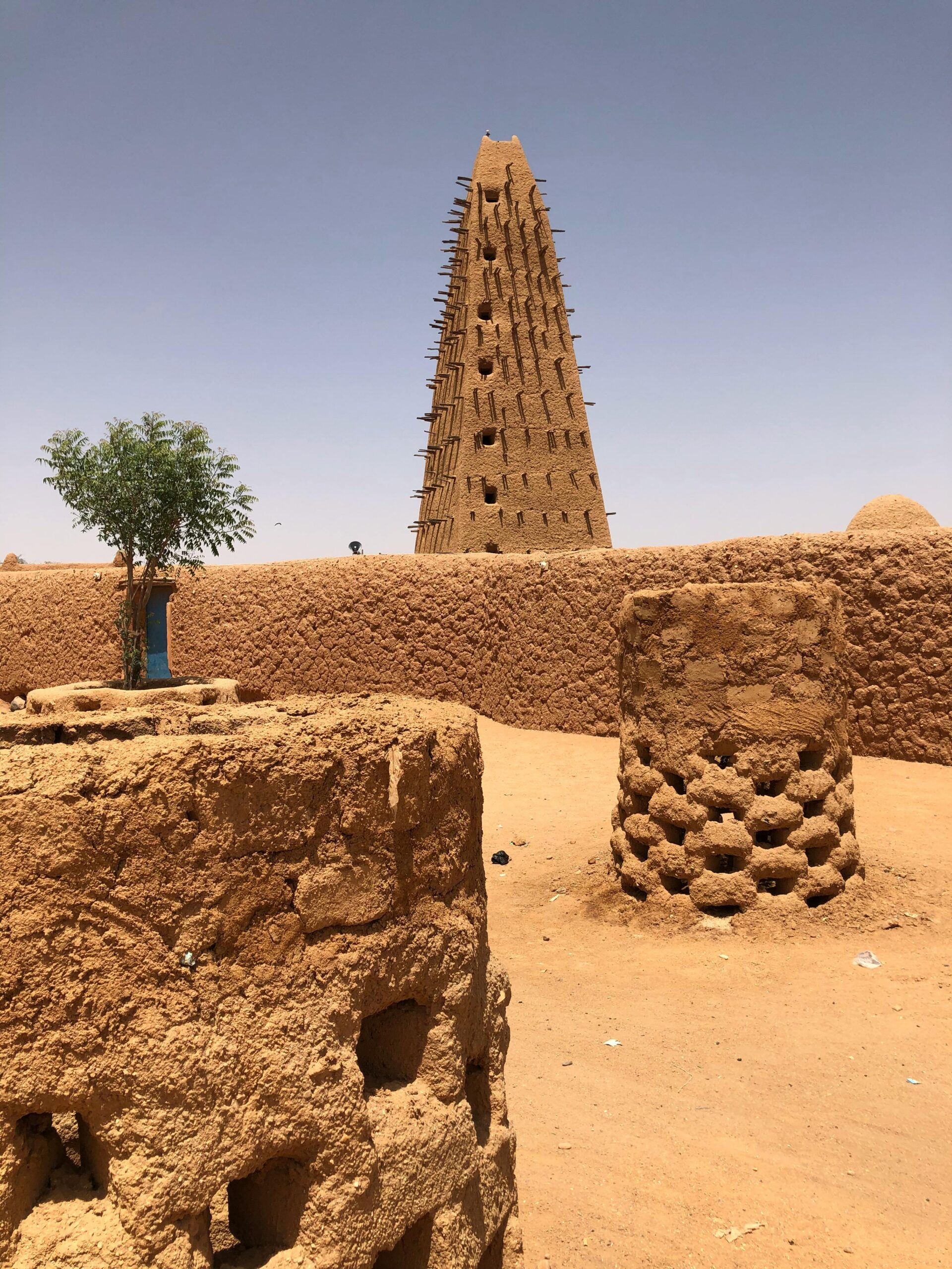 A view of the historical Agadez Mosque amidst desert sand and clear skies.
